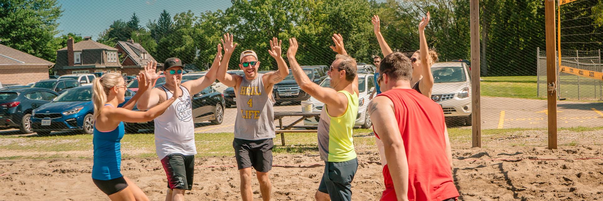 Beach volleyball team giving a group high five.