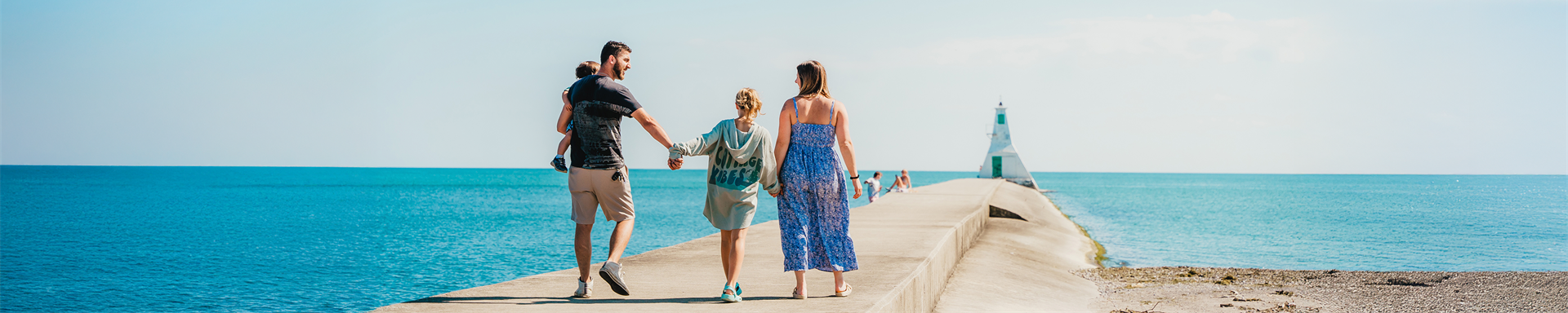family walking down the sunny Erieau pier