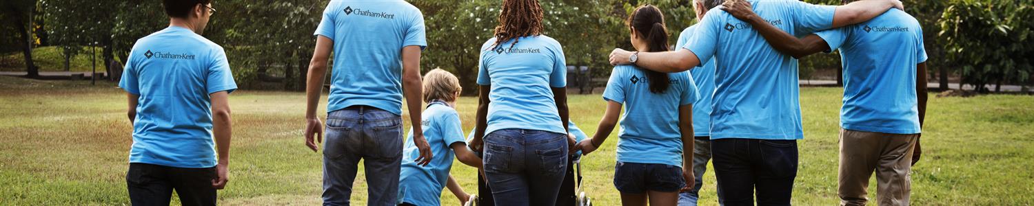 Image of a group of diverse people walking in the park wearing Chatham-Kent shirts.