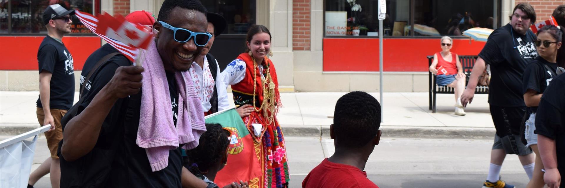 A group of people in a Canada Day parade with flags.