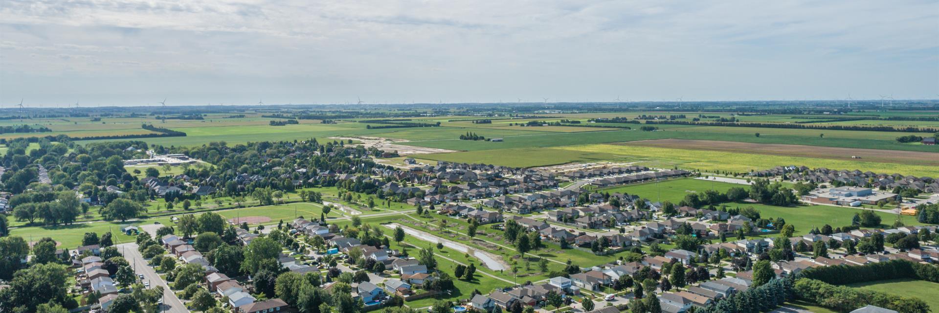 Drone shot of Chatham-Kent of green neighbourhoods and fields and a blue sky above.