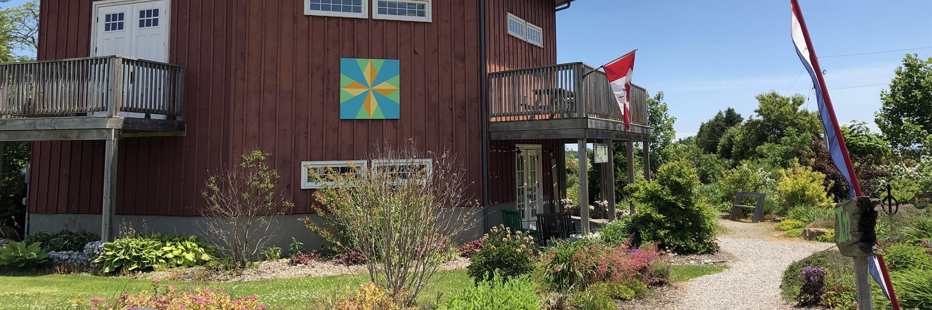 A red eight-sided barn surrounded by a garden.