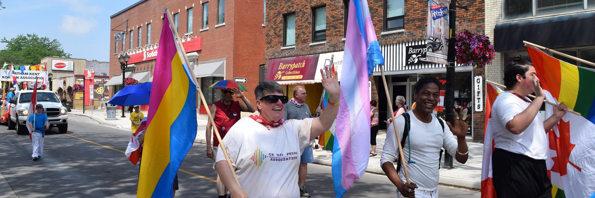 People wearing CK Gay Pride Association shirts and holding a banner in a parade.