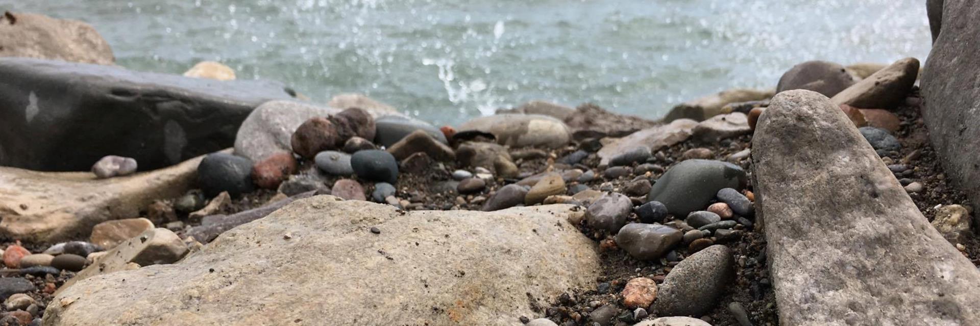 Close up of rocks along a beach and water splashing against them.