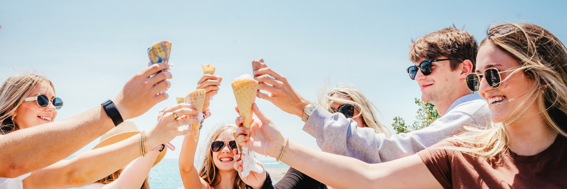 Group of young people walking through a crowded street lined with antique cars.