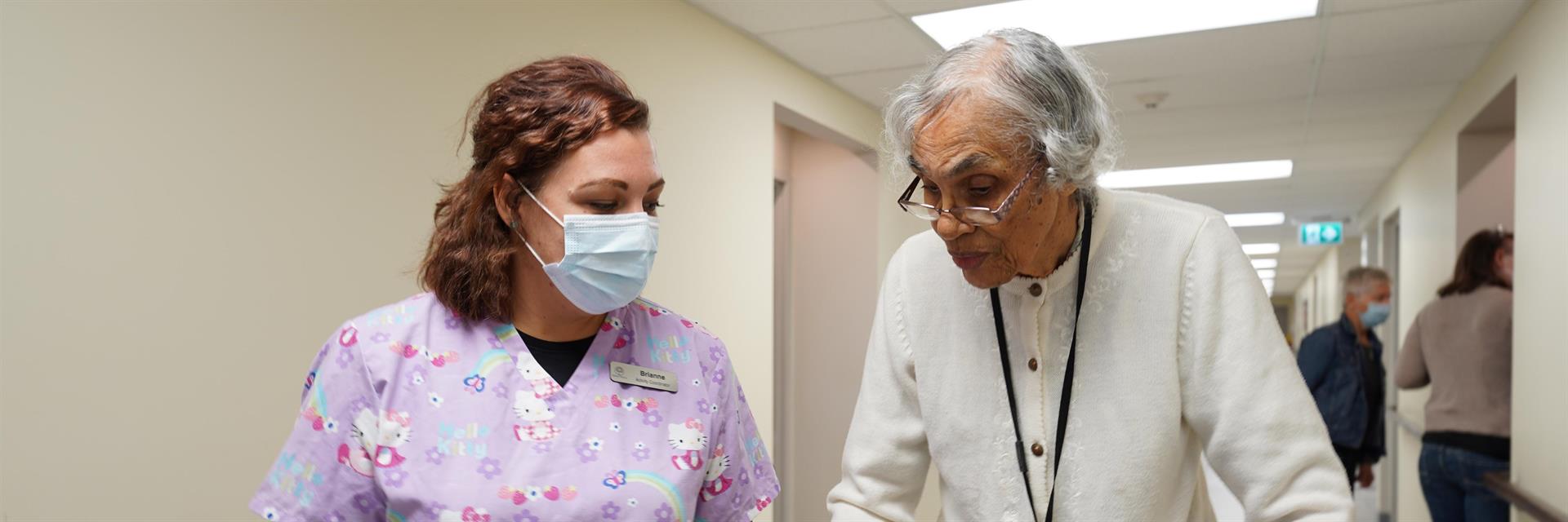 A PSW talking to a resident in the hallway.