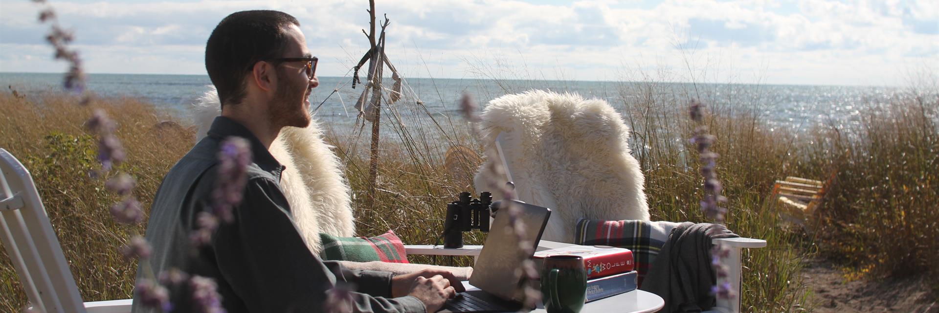 A man sitting at the beach working.