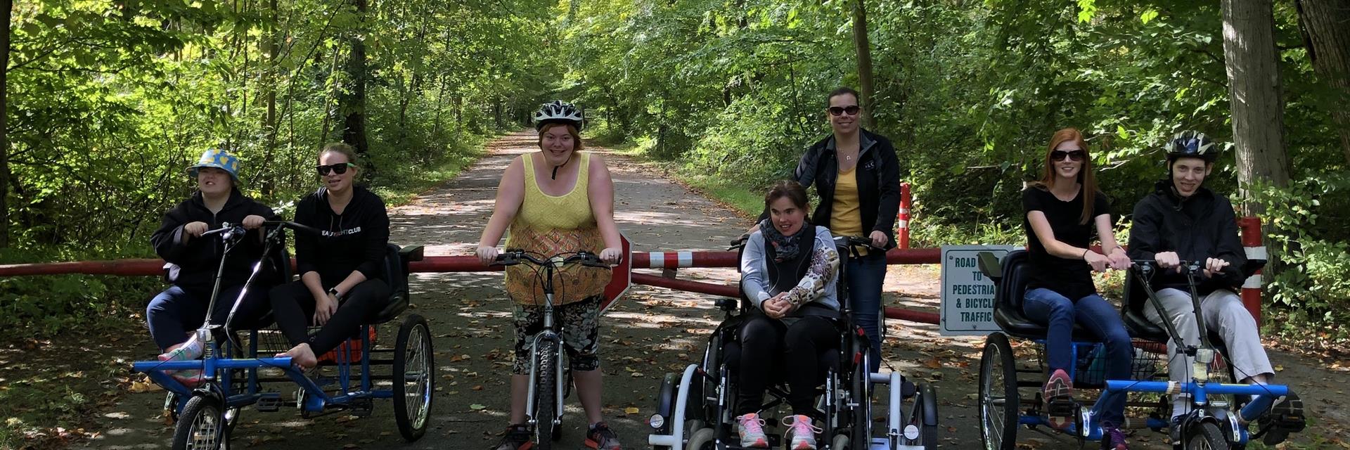 Group of people on different styles of bikes and wheelchairs exploring a path.