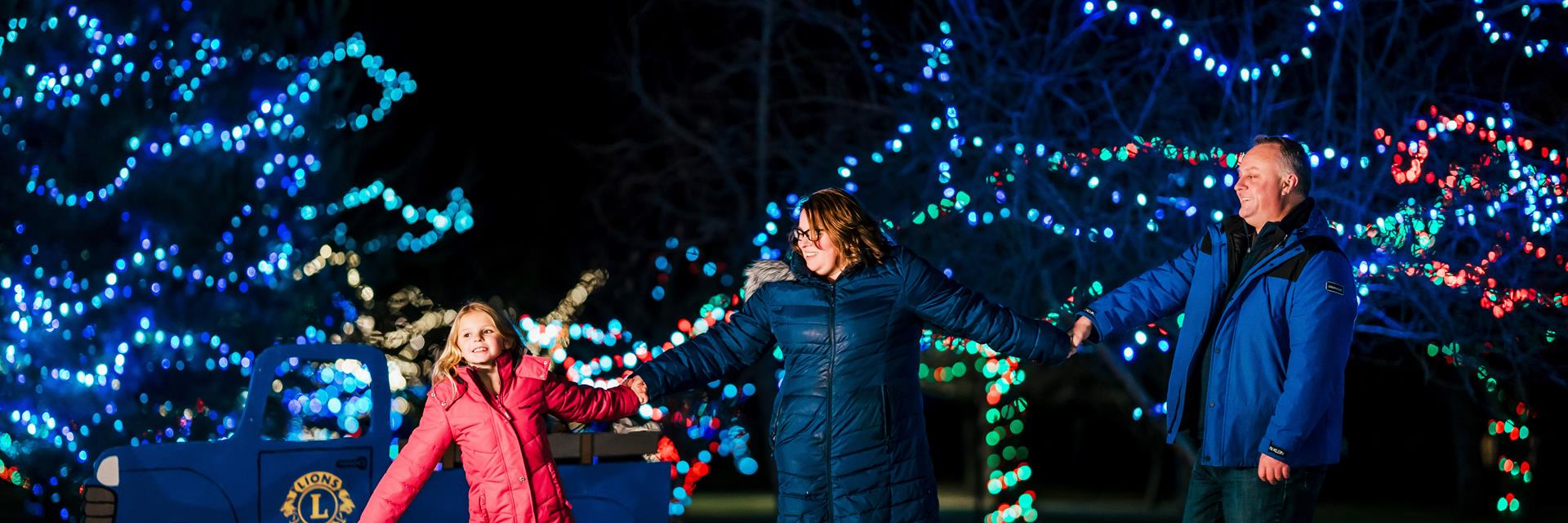 family with christmas lights behind them 