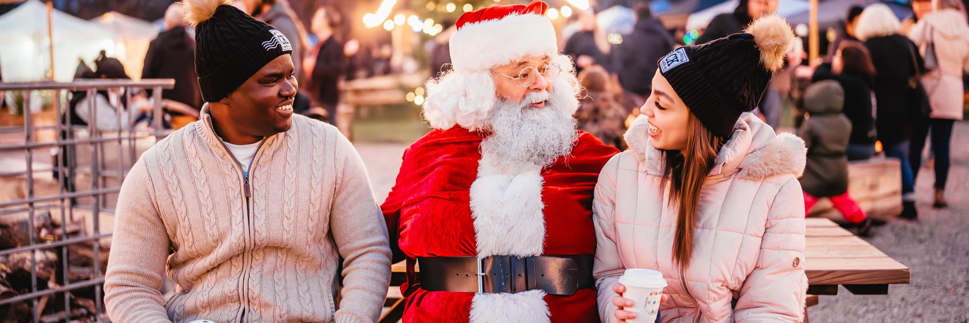 santa and two others sitting outside on a picnic table 
