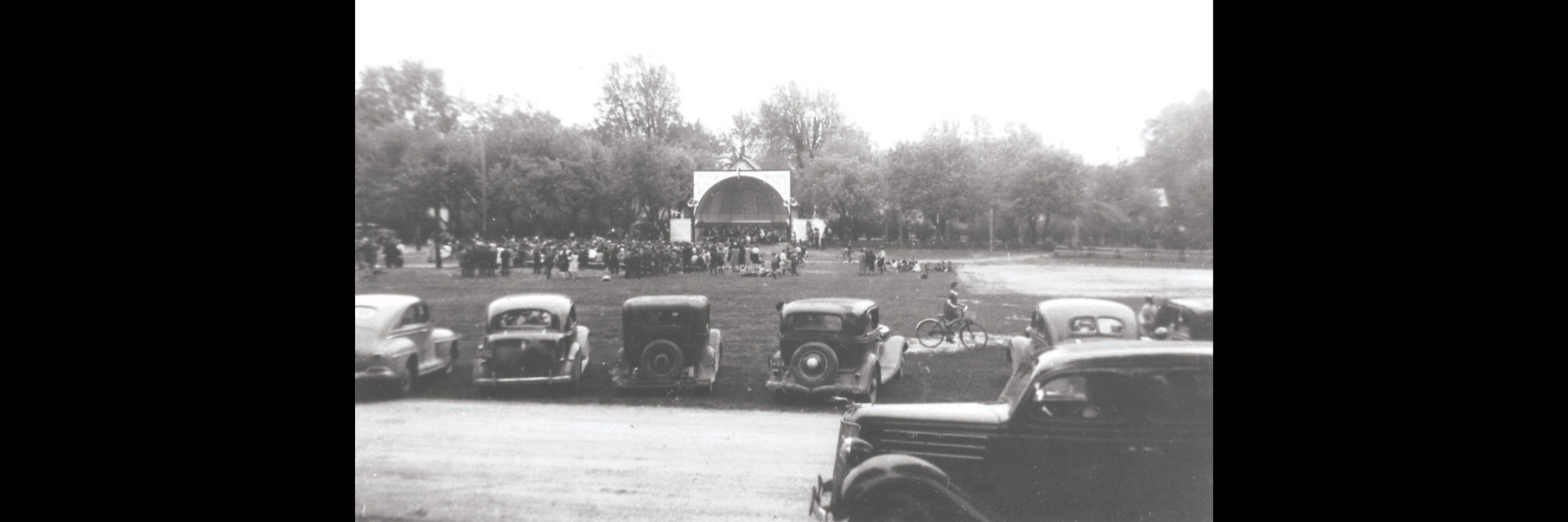 black and white photo of bandshell at jackson park with cars and people