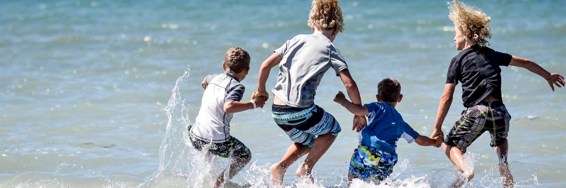 a family jumping into the water on the beach