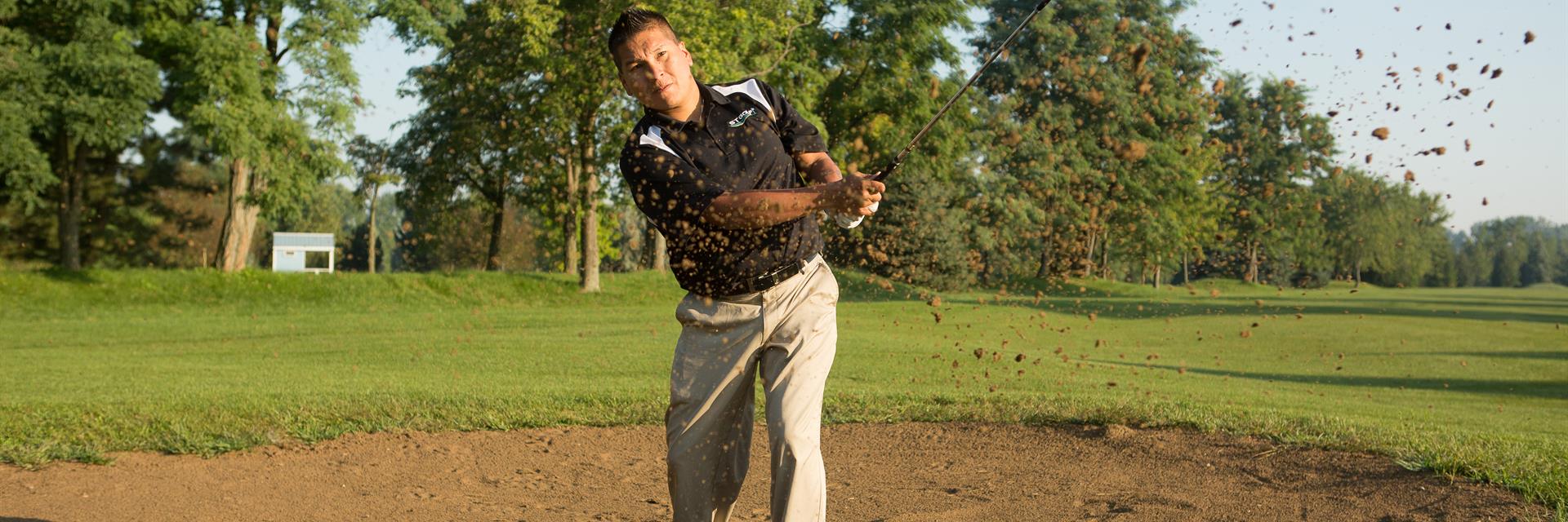 golfer hits a ball out of a sand trap 