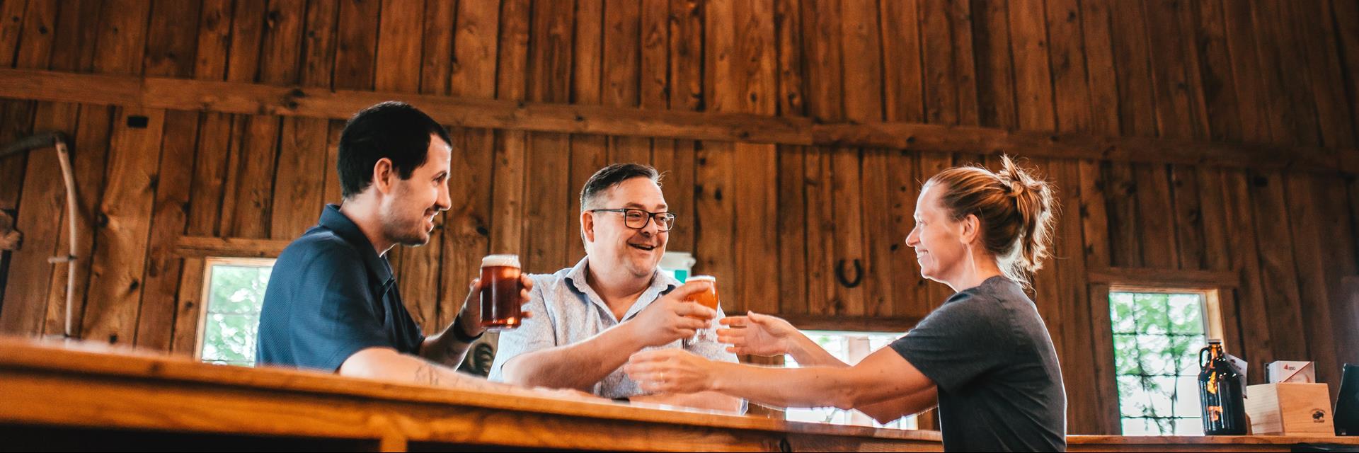 two men sitting at a bar with a woman in the background