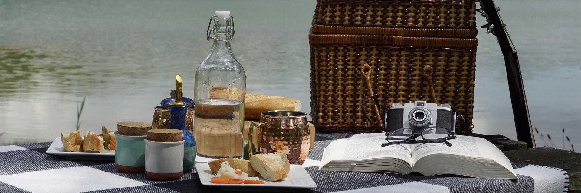 picnic basket on a picnic table in front of a lake